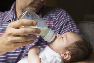 Close up of father bottle feeding baby