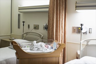 Mixed race wrapped in blanket in hospital crib