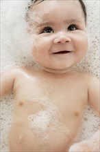 Close up of mixed race baby in bubble bath