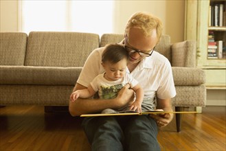 Father reading to son on living room floor