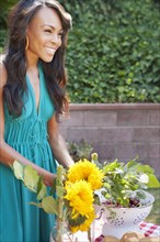 Smiling woman gathering flowers in backyard