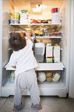 Mixed race baby boy exploring refrigerator