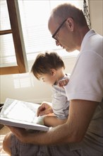 Father reading book to son in lap