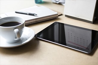 Tablet computer on table with book and coffee