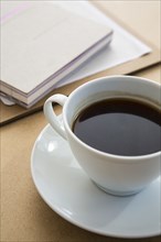 Cup of coffee on table with book