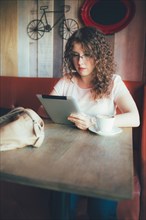 Woman using digital tablet in cafe