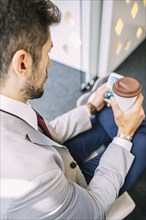 Caucasian businessman drinking coffee and using cell phone