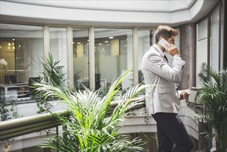 Caucasian businessman talking on cell phone on office balcony