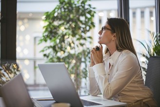 Caucasian businesswoman thinking at desk in office