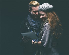 Couple wearing warm clothing using digital tablet