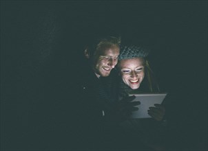Couple wearing warm clothing using digital tablet at night