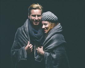 Smiling couple wrapped in blanket