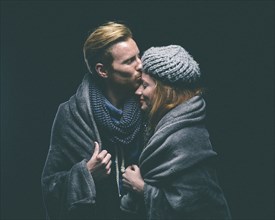 Smiling couple wrapped in blanket kissing