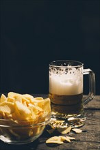 Glass of beer with bowl of potato chips