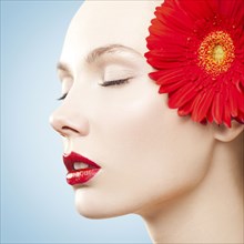 Caucasian woman with red lipstick wearing matching flower