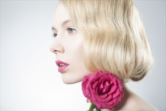 Caucasian woman with pink lipstick holding matching flower