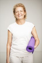 Smiling woman holding exercise mat