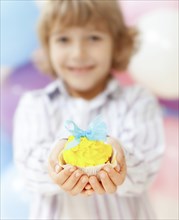 Close up of boy holding decorated cupcake