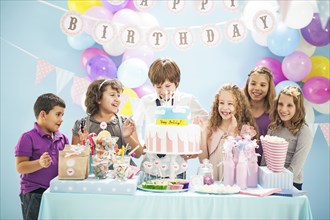 Children smiling near cake and gifts at birthday party