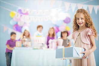 Girl holding wrapped gift at birthday party