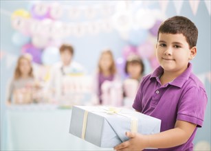 Boy holding wrapped gift at birthday party