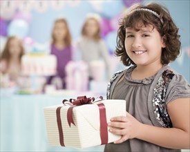 Girl holding wrapped gift at birthday party