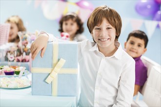 Boy smiling with wrapped gift at birthday party