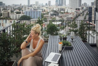 Caucasian woman talking on cell phone on balcony