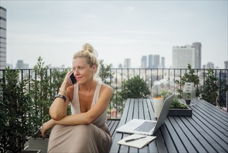 Caucasian woman talking on cell phone on balcony