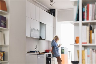 Woman using digital tablet in kitchen