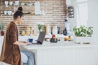 Caucasian woman using laptop in kitchen