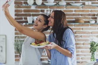 Caucasian women taking selfie in kitchen with pasta