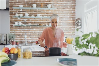 Older Caucasian woman cooking spaghetti in kitchen