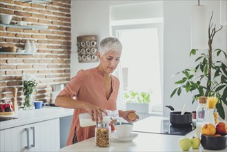 Older Caucasian woman pouring milk in kitchen
