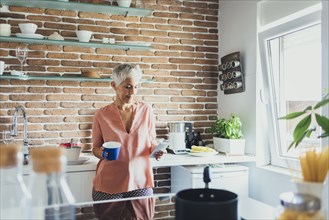 Older Caucasian woman using cell phone in kitchen