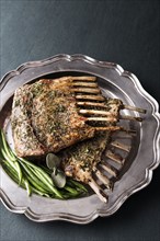 Rack of lamb and green beans on silver platter