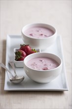 Bowls of fruit soup with strawberries and spoons