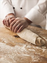 Hands of baker rolling dough