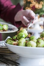 Hand serving brussels sprouts with spoon