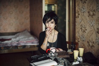 Caucasian woman smoking cigarette in bedroom