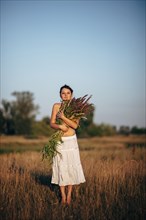 Caucasian woman carrying flowers in rural field