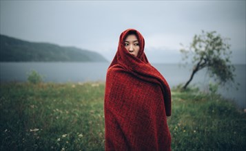 Caucasian woman wrapped in blanket in rural field