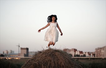Caucasian woman jumping on haystack