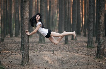 Caucasian woman floating in forest