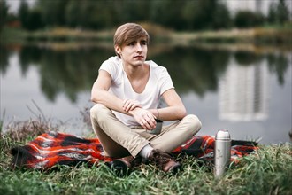Caucasian man sitting near rural pond