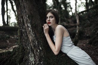 Caucasian woman leaning on tree in forest