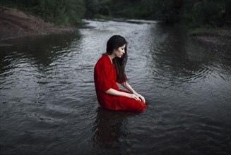 Caucasian woman sitting in remote stream