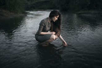 Caucasian woman crouching in remote stream