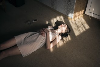 Caucasian woman laying in sun spot on floor