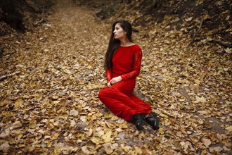 Caucasian woman sitting in autumn leaves